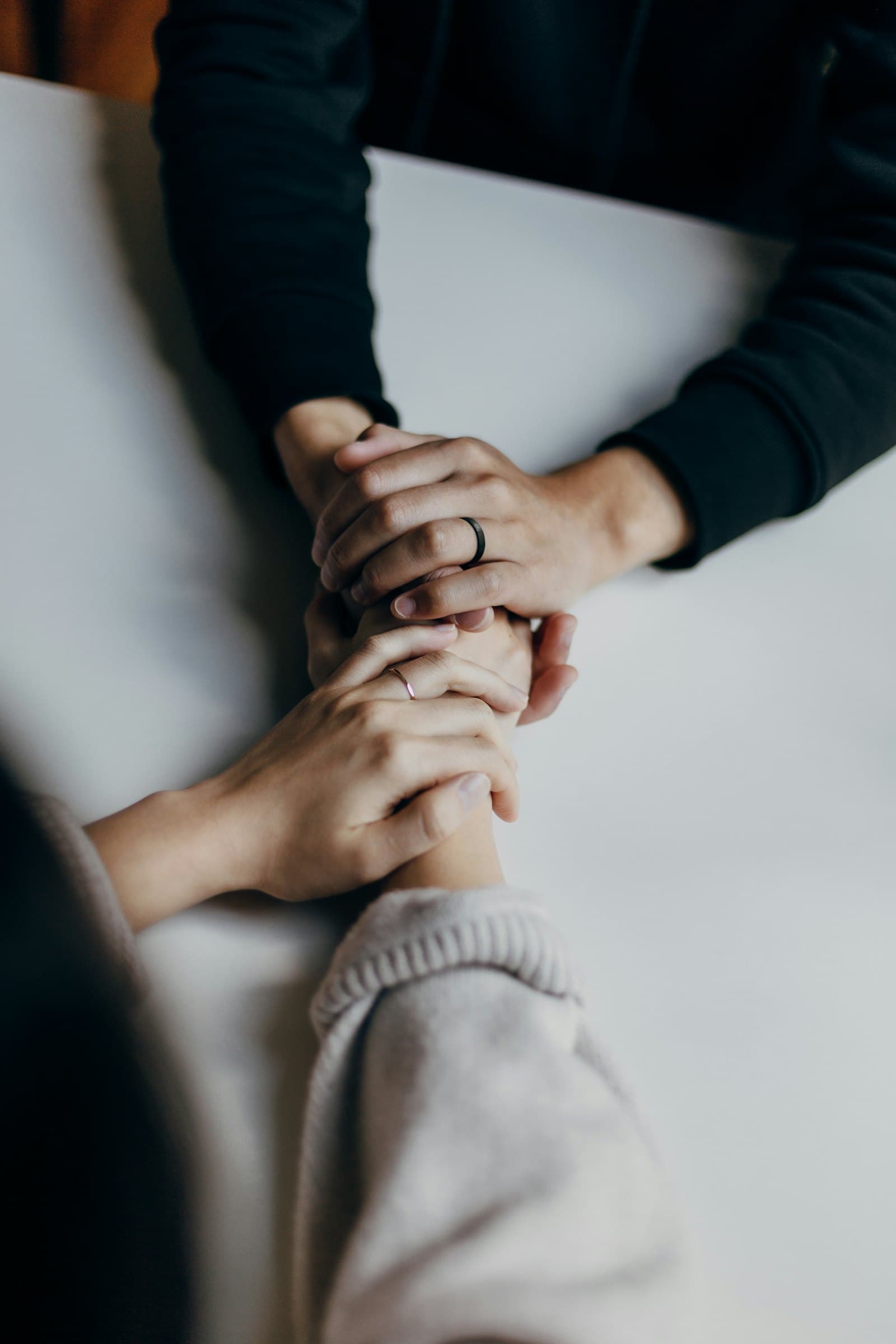Two pairs of hands gently clasped together in a moment of care.